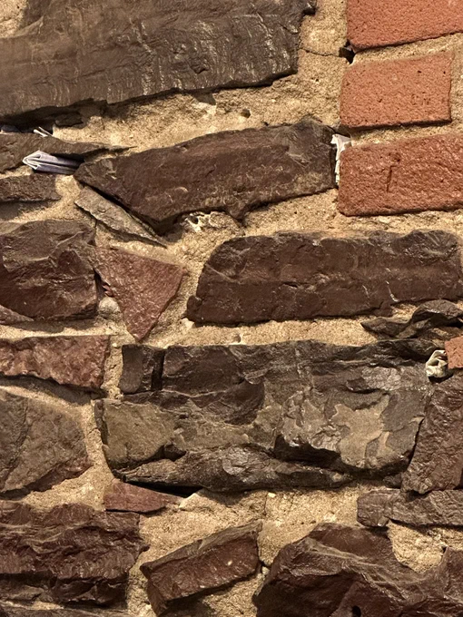 A stone wall with small pieces of paper stuck in various crevices.