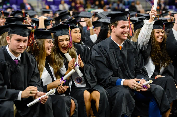 Students smiling and cheering during the graduation ceremony.
