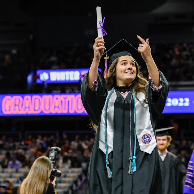 Graduate holding up their degree on the stage.