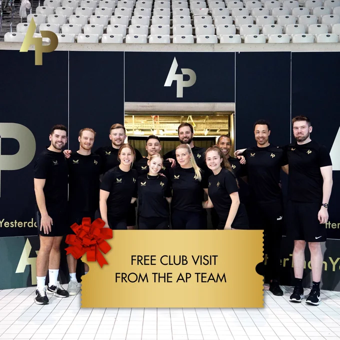 12 members of the AP Race Club Team standing together with their arms over each other. A golden ticket is in the bottom centre of the image which contains the text: “free club visit from the AP Team”.