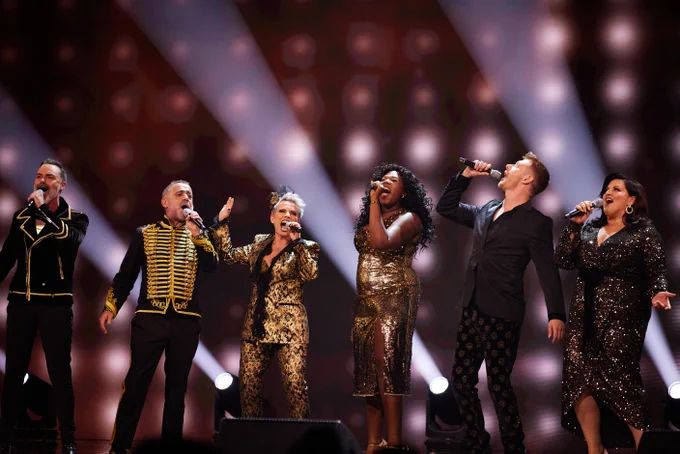 Team Corrie belting out a song on stage.