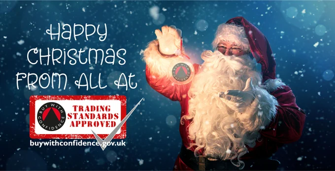 Santa Claus holds a bauble with the Buy With Confidence logo in it. Text reads Happy Christmas from all at Buy With Confidence Trading Standards Approved