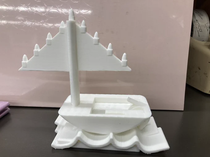 3d printed sail boat. Sailboat sits on top of a wave. There are four menorah candles on each of the two sails, with one more candle (the Samash) in the middle, on the mast.