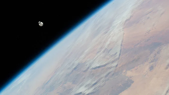 The SpaceX Dragon cargo craft, loaded with over 7,700 pounds of science, supplies, and cargo, approaches the International Space Station while orbiting 259 miles above the African continent. Earth dominates this photo, with only a small portion of the photo (the upper left corner) showing the darkness of space. The spacecraft is but a small, white spherical shape against that black background. Credit: NASA