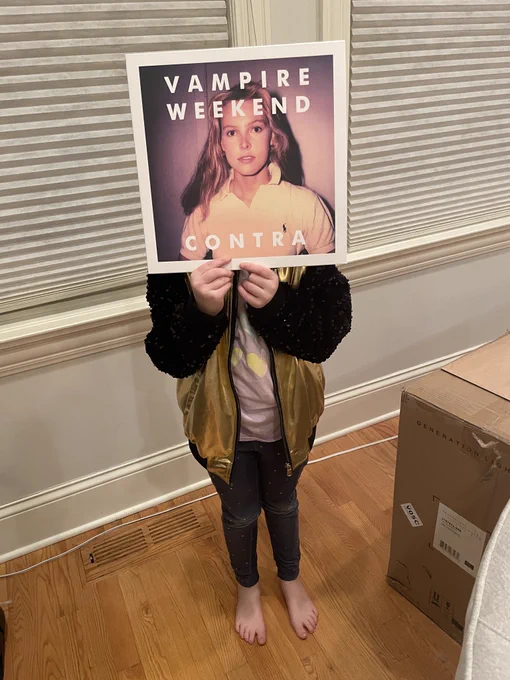 7 year old holding up Vampire Weekend’s album Contra