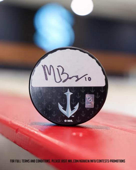 photo of a matty beniers signed puck, with text at the bottom reading "for full terms and conditions, please visit NHL.com/kraken/info/contests-promotions"
