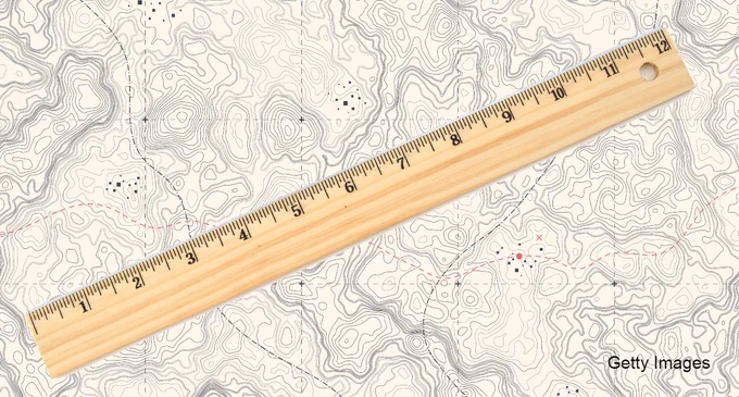 Ruler with land map in the background. Credit: Getty Images.