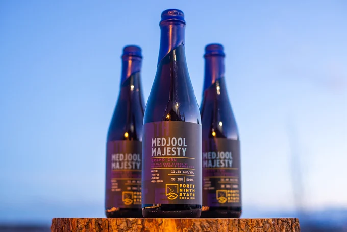 Medjool Majesty is a decadently rich, viscous Belgian Dark Strong Ale crafted with medjool dates and handpicked Alaska spruce tips. Dark fruit, toffee, molasses and cherry mingle with fresh red berry spruce tip notes and warming spices to create layers of majestic complexity. We recommend buying at least two bottles: one to drink immediately and one to cellar for two to twelve years. 