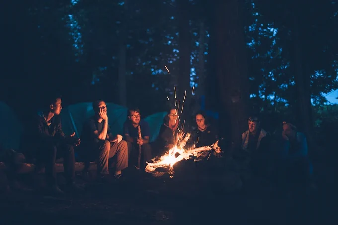 Royalty free image from Unsplash - credit in main body of the tweet. Image shows campers around a camp fire.