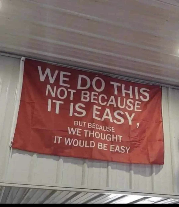 Banner hanging from ceiling that reads “WE DO THIS BOT BECAUSE IT IS EASY, BUT BECAUSE WE THOUGHT IT WOULD BE EASY”