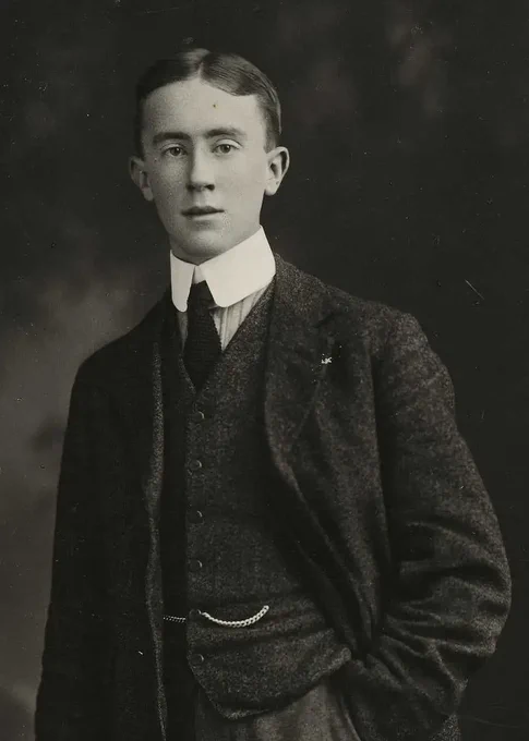 A vintage photograph of young J. R. R. Tolkien in three-piece suit, posing formally with one hand inside his pocket.