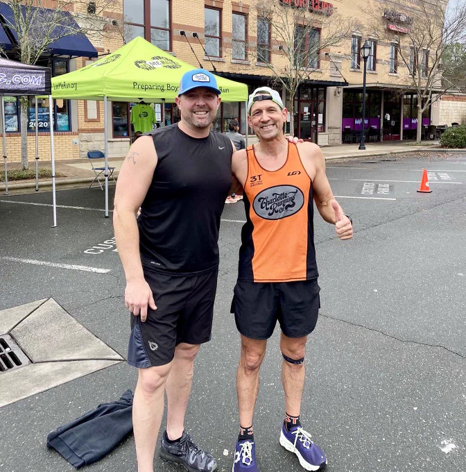 Donny and Paul are smiling and standing outside in front of the run store, pop up tents are behind them