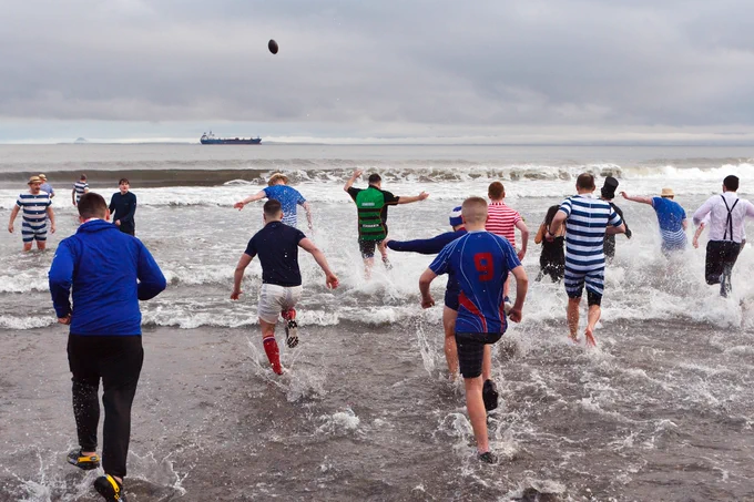 People splashing in the water running out into the sea as part of the loony dook