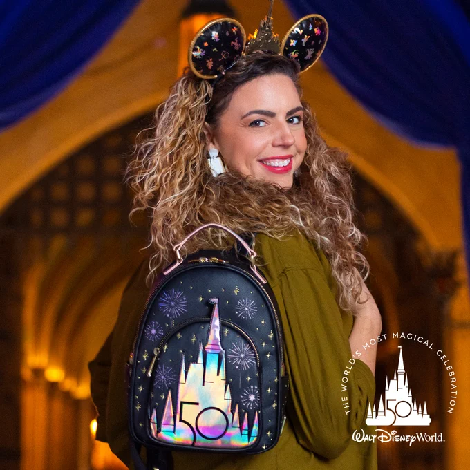 Woman smiling while wearing the Walt Disney World 50th Grand Finale Ear Headband and Loungefly Backpack