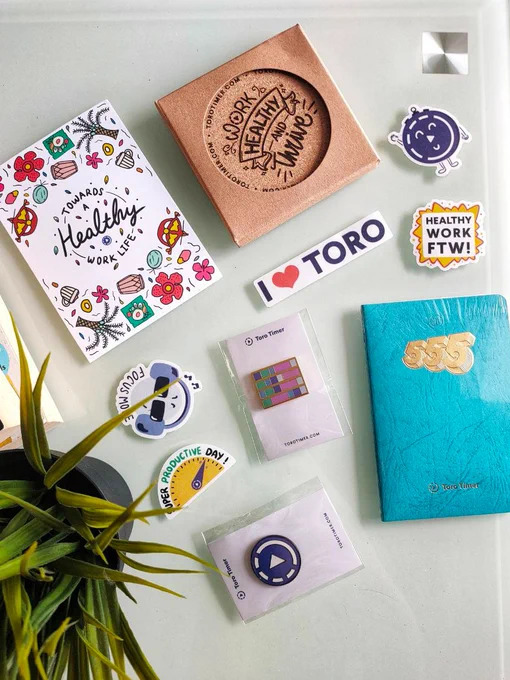 Swag pack from time tracking app called toro timer. Pack contains stickers, notebook, pins, and coasters