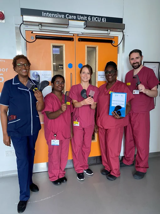 Ginny stood in her dark blue nursing uniform, joined by four colleagues in their red nursing uniforms. All are holding different types of comb while smiling at the camera. 