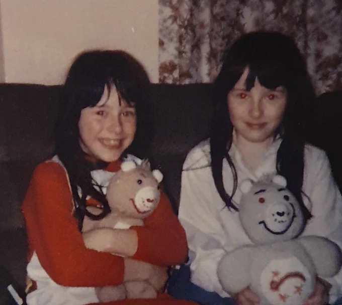 Two black haired girls cuddle knitted toys 