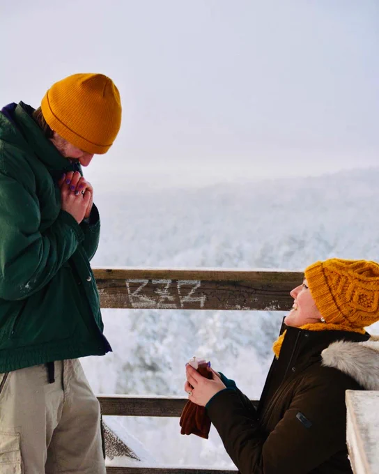 Bethany proposing to James in the middle of a snowy forest.
