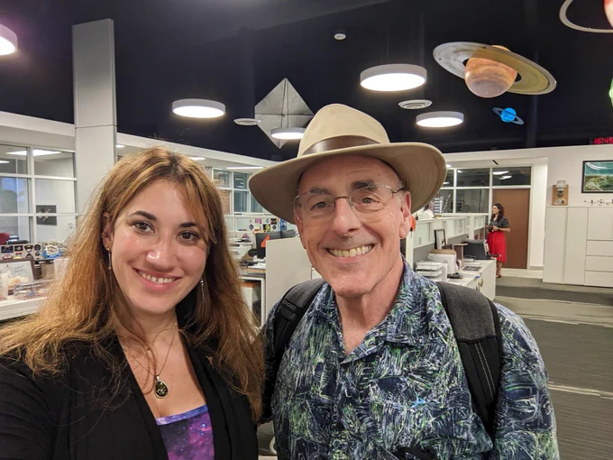 This is an image of Sarah Al-Ahmed, the new host of Planetary Radio, with Mat Kaplan, the former host of the show, smiling together in The Planetary Society's headquarters.