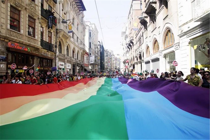 Istanbul Pride 2008. An enormous Pride flag carried by people covers the entire street. Image by Turkish Flame via Wikimedia Commons.