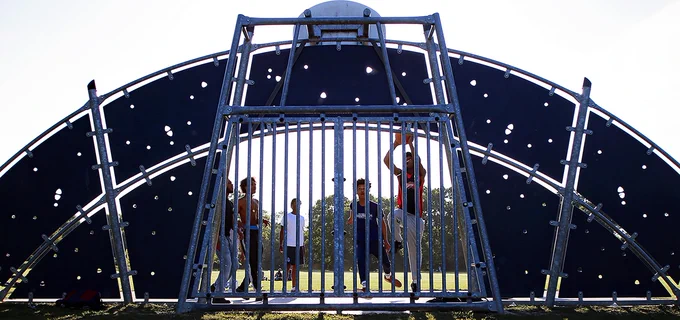 Photo of children playing basketball at a park, with one shooting into the hoop.