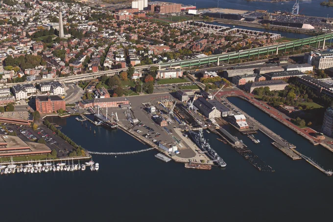Aerial view of the Charlestown Navy Yard. Centered in the photograph is Pier 1 with the USS CASSIN YOUNG to the right and USS CONSTITUTION to its left.