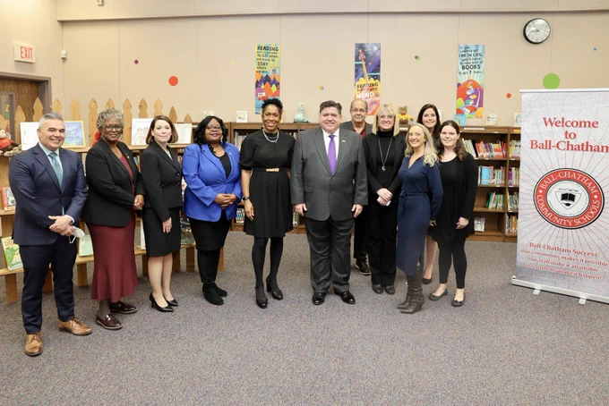 A group photo with Governor Pritzker, Lt. Governor Stratton, local legislators and school district staff in a classroom.