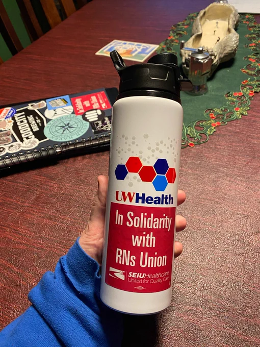 A white water bottle with a blue and red logo that says UW Health. The bottom of the logo is overlaid with a red sticker that says “in solidarity with nurses union.”