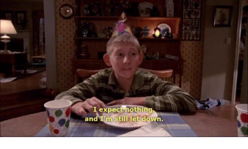 Screen capture from the show Malcolm in the middle. There is a character sitting at a table with a birthday hat, looking at an empty plate, and the caption says “I expect nothing but still I am let down.”