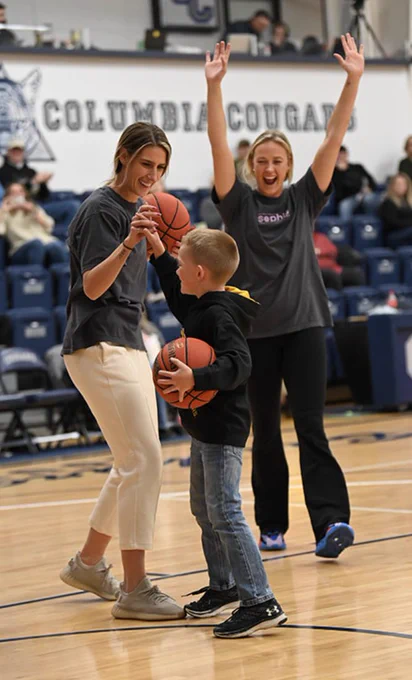 Sophie and Lindsey Cunningham cheering young basketball player