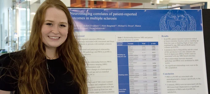 Master's student Taylor Wicks stands near her poster