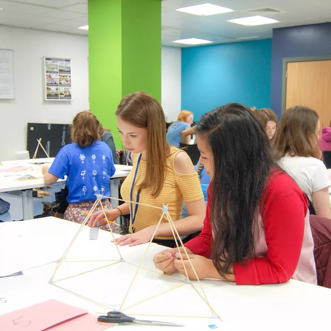 two girls in a classroom working on a practical engineering project