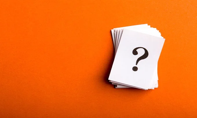 A pile of white cards. The top card has a question mark on it