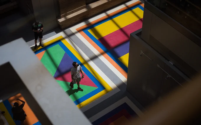 Person walking across a colorful floor, photo shot from above.