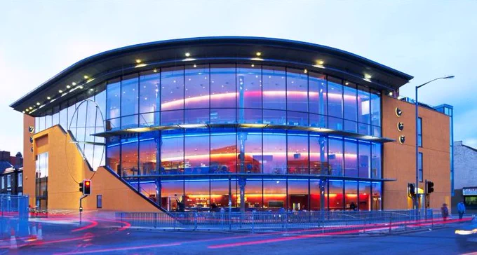 Exterior of ARC in Stockton, a glass fronted building lit with neon lighting from inside.