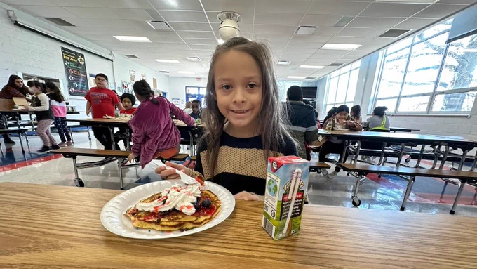 Dumfries Elementary School student eats a pancake during a breakfast for outstanding attendance.