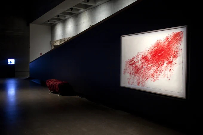 Framed art hanging in Mona showing red hand prints are scattered across a white background.