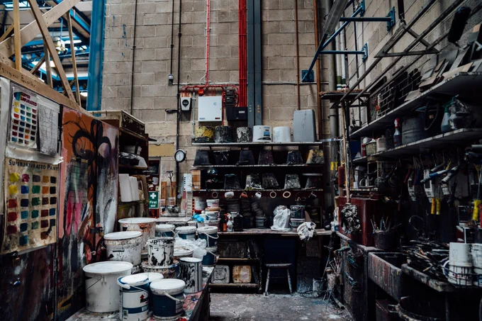 A workshop at Leeds Playhouse packed with set building materials like paint pots, colour charts and brushes.