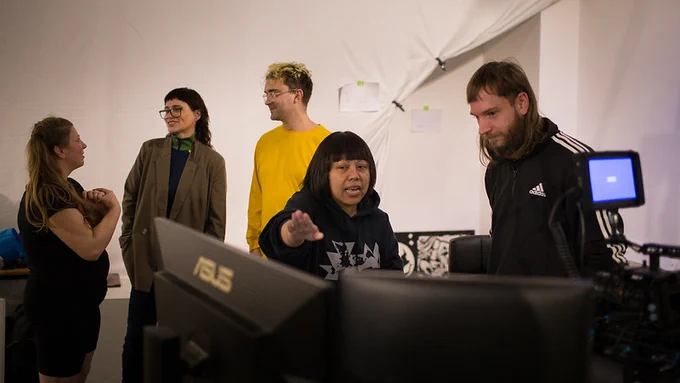 Five people in discussion and looking at multiple computer screens after a dance performance by Lucie Lee. Photo Credit: Martin Singleton.
