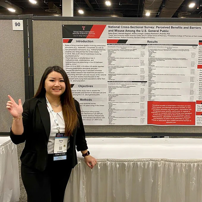 Female TTUHSC pharmacy student stands in front of her research poster at a conference.