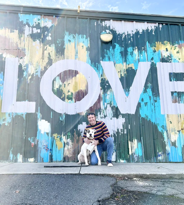 Jay and Petey the dog are posed in front of the Love Mural at Project 658 on Central Ave.