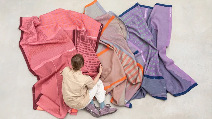Image shows a person working with textiles which feature bright colours and lively patterns 