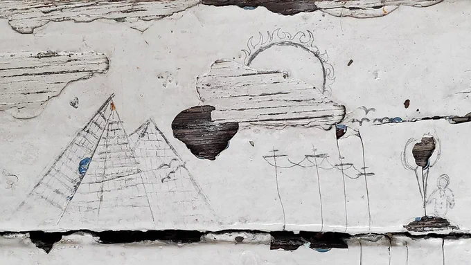 This photo shows a drawing on the surface of a windowsill. The paint-cracks of which were creatively incorporated into a visual composition consisting of pyramids, overhead power lines, the sun and a character holding a balloon. Never stop noticing creativity. Explore http://www.designfeast.com