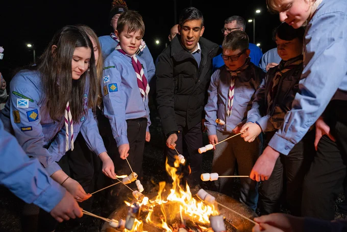 UK Prime Minister Rishi Sunak toasting marshmallows around a fire with Scouts in Scotland.