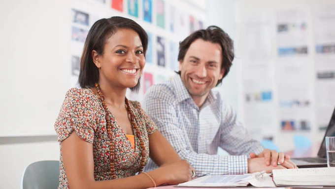 2 volunteers at a desk smiling