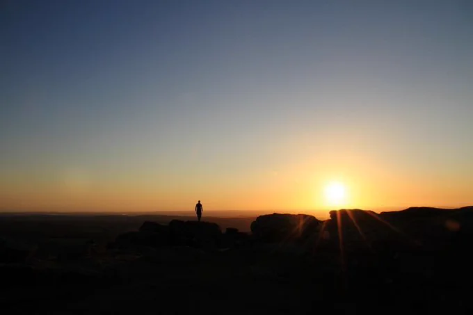 Sunset on Dartmoor. Lone shadowed figure admiring the sunset.