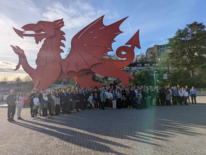 A group of people stood in front of a large, red, dragon statue