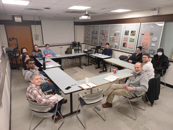 A photo of Gries lab members sitting in a meeting room around a square table. Left to right are Mikhaela, Thet Thet, Sam, Anand, Regine, Claire, Emma, Emmanuel, Gerhard, Andi, Steve, and Saif