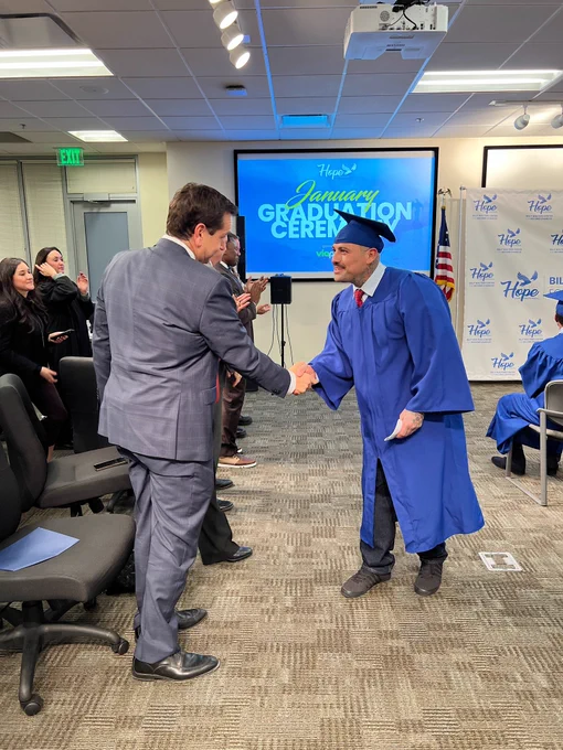 Secretary Aguilar shakes hands with graduate