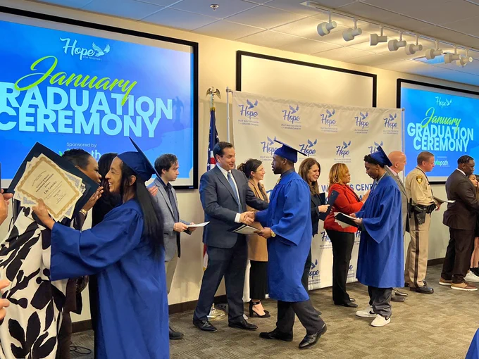 Secretary Aguilar shakes hands with graduate